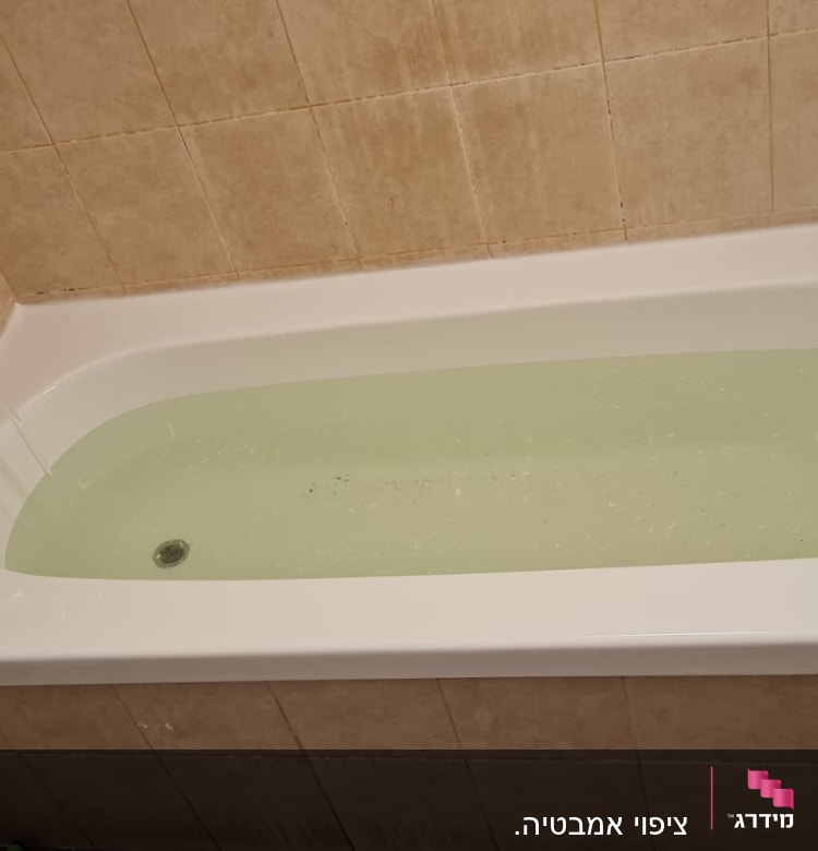 אמבטיה מלאה מים עם ברז פתוח על קיר אריחים